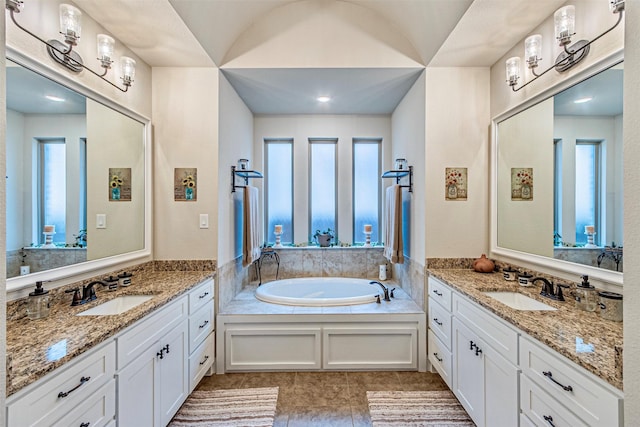 full bath featuring tile patterned floors, two vanities, a bath, and a sink