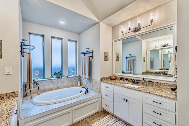 bathroom with tile patterned floors, a bath, and vanity