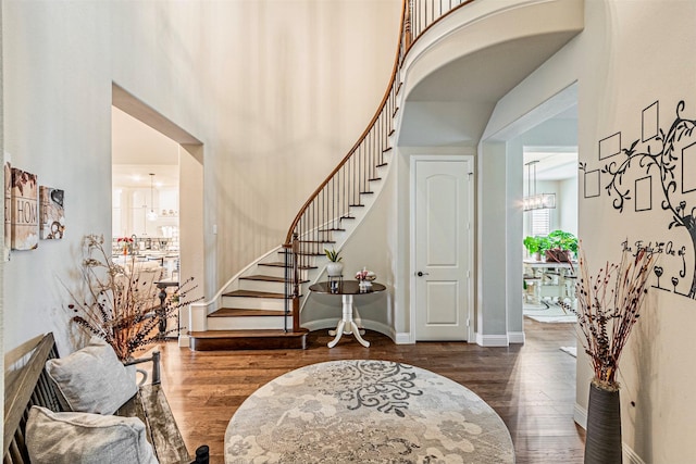 foyer with dark wood finished floors, stairway, baseboards, and a towering ceiling