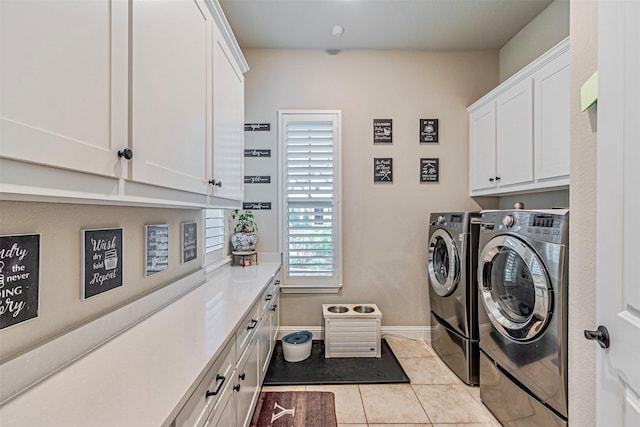 clothes washing area featuring baseboards, cabinet space, light tile patterned flooring, and washing machine and clothes dryer