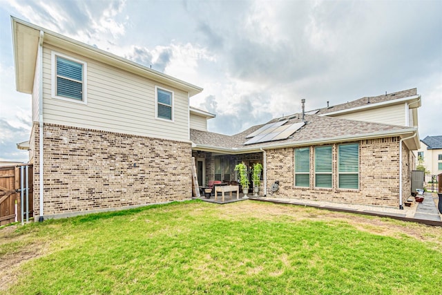 back of house with a patio, fence, solar panels, a lawn, and brick siding