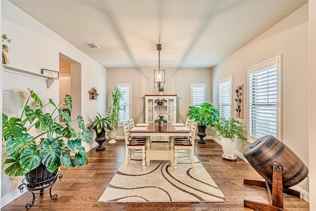 dining space with wood finished floors, visible vents, and baseboards