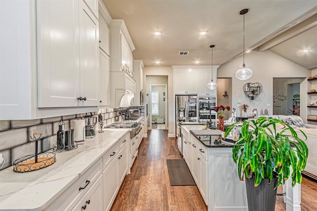 kitchen featuring an island with sink, lofted ceiling with beams, wood finished floors, white cabinetry, and hanging light fixtures