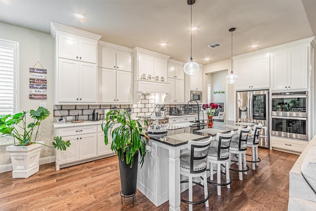 kitchen with stainless steel appliances, a kitchen bar, visible vents, and decorative backsplash