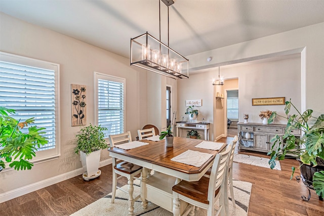 dining room with baseboards, a notable chandelier, and wood finished floors