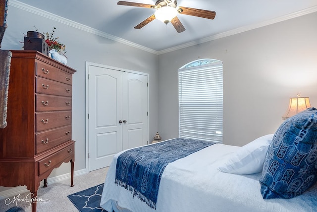 carpeted bedroom with ornamental molding, a closet, and ceiling fan