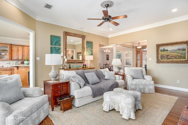 living room featuring ceiling fan with notable chandelier, crown molding, light hardwood / wood-style floors, and decorative columns