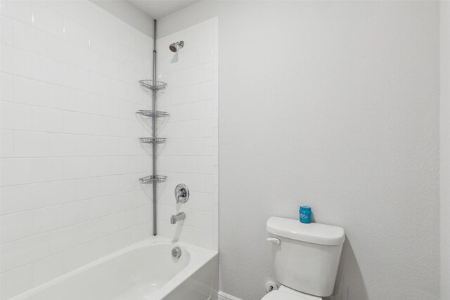 bathroom featuring tiled shower / bath combo and toilet