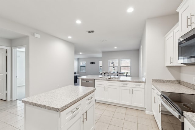 kitchen with white cabinetry, sink, stainless steel appliances, a kitchen island, and light tile patterned flooring