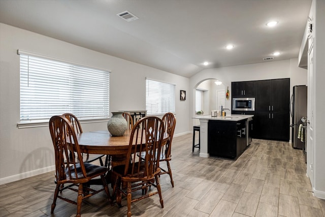 dining space with light wood-type flooring and vaulted ceiling