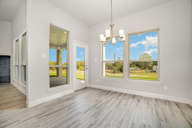 unfurnished dining area with an inviting chandelier and light hardwood / wood-style flooring