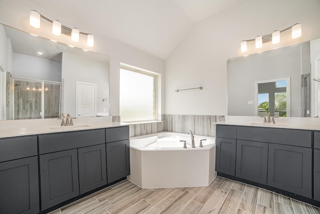 bathroom with separate shower and tub, plenty of natural light, hardwood / wood-style floors, and vaulted ceiling