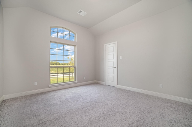 carpeted spare room featuring vaulted ceiling