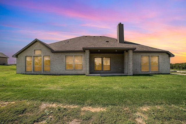 back house at dusk featuring a yard