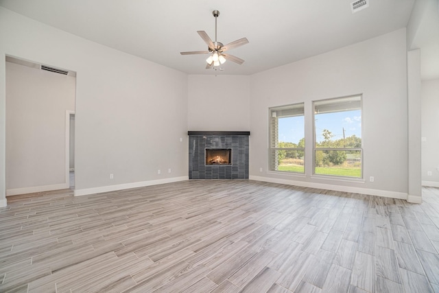 unfurnished living room featuring ceiling fan, a fireplace, and light hardwood / wood-style flooring