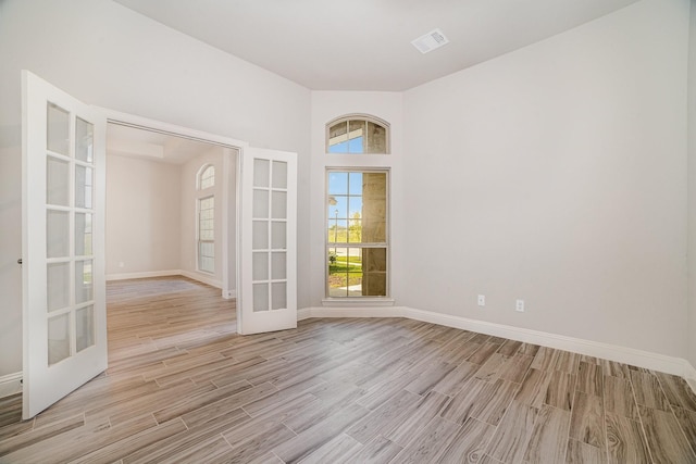 spare room featuring french doors and light hardwood / wood-style flooring