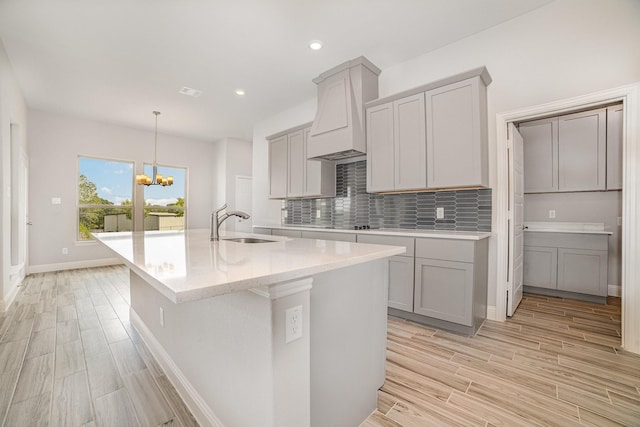 kitchen featuring gray cabinetry, light hardwood / wood-style flooring, and a chandelier