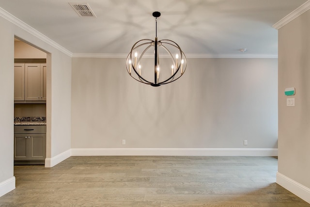 unfurnished dining area with a chandelier, light hardwood / wood-style flooring, and ornamental molding