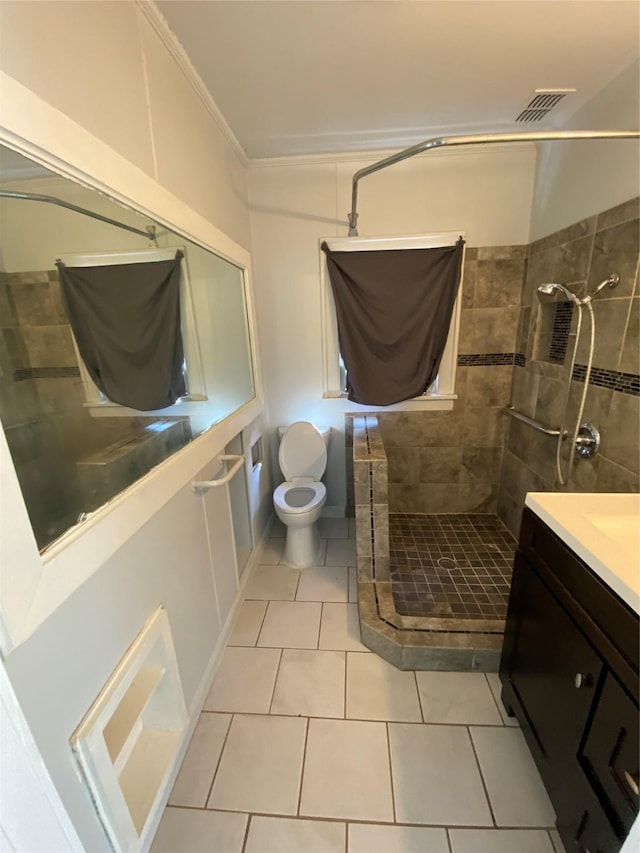 bathroom featuring ornamental molding, a tile shower, vanity, tile patterned flooring, and toilet