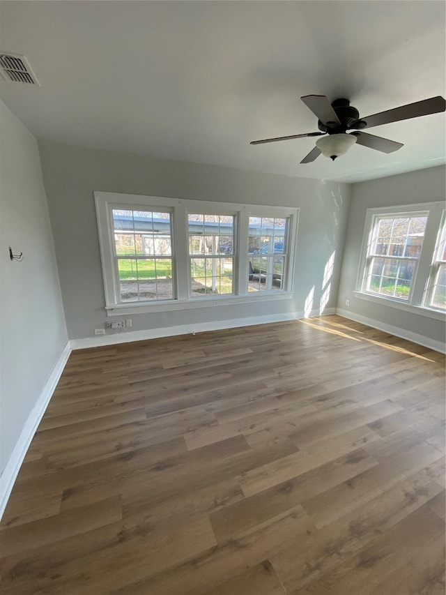 unfurnished room with dark hardwood / wood-style floors, a wealth of natural light, and ceiling fan