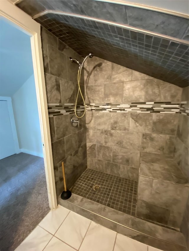 bathroom featuring a tile shower, vaulted ceiling, and tile patterned floors