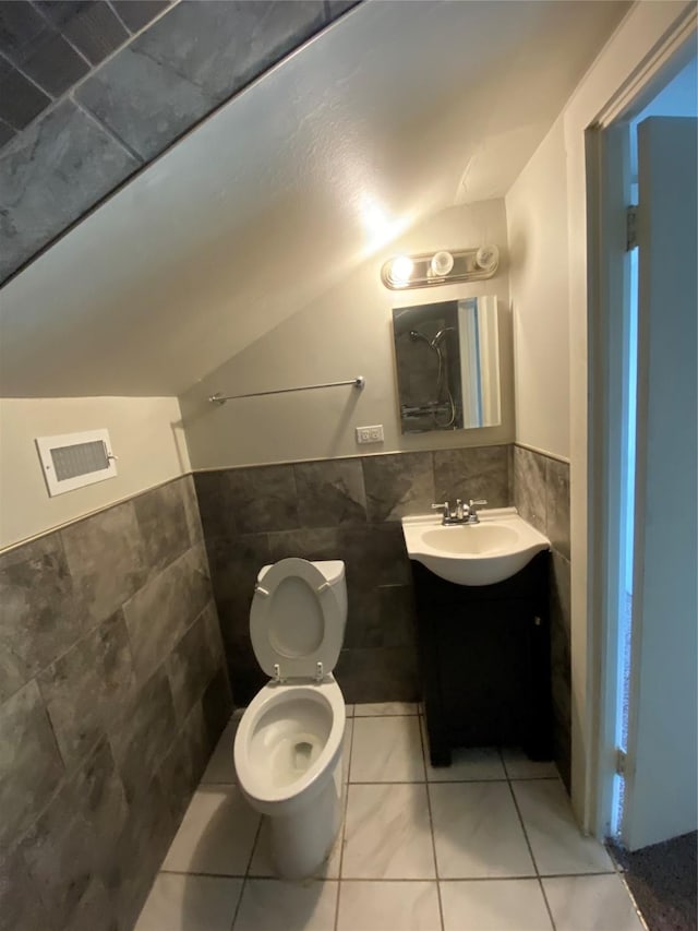 bathroom featuring vanity, tile walls, tile patterned flooring, toilet, and lofted ceiling