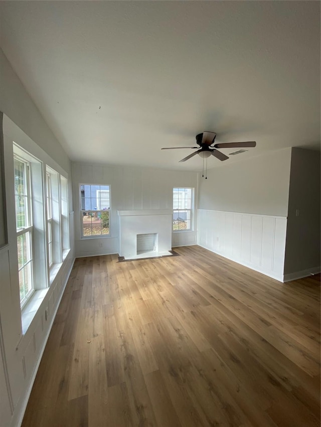 unfurnished living room featuring a wealth of natural light, wood-type flooring, vaulted ceiling, and ceiling fan