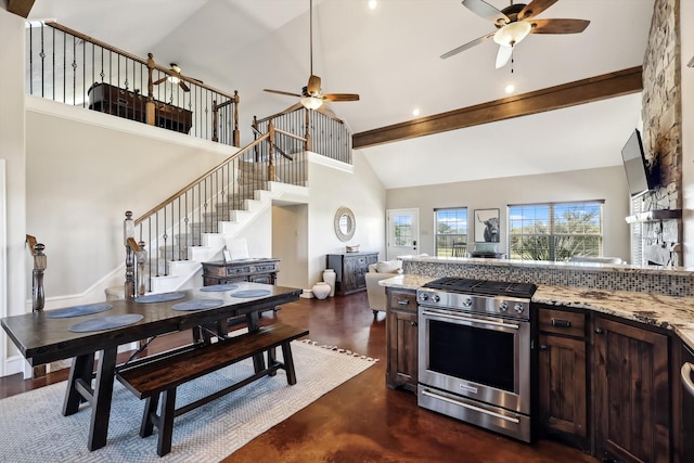 kitchen featuring gas range, dark brown cabinetry, light stone countertops, and high vaulted ceiling