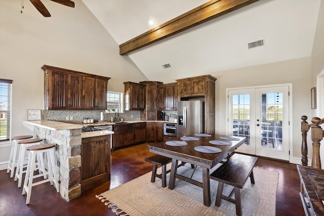 kitchen featuring stainless steel appliances, a breakfast bar area, decorative backsplash, and french doors