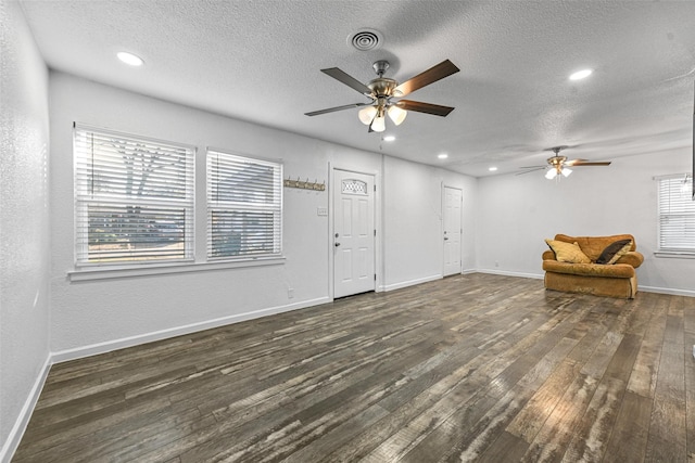 interior space featuring ceiling fan, dark wood-type flooring, and a textured ceiling