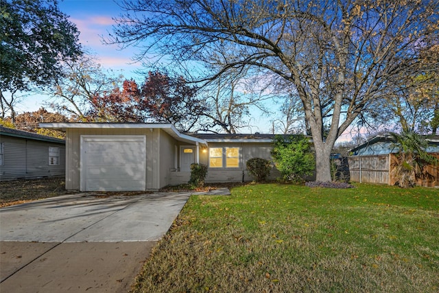 ranch-style home featuring a garage and a lawn