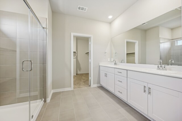 bathroom with a shower with door, vanity, and tile patterned flooring