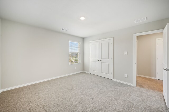 unfurnished bedroom featuring a closet and light colored carpet