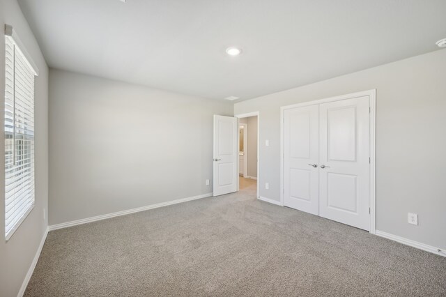 unfurnished bedroom featuring light colored carpet and a closet