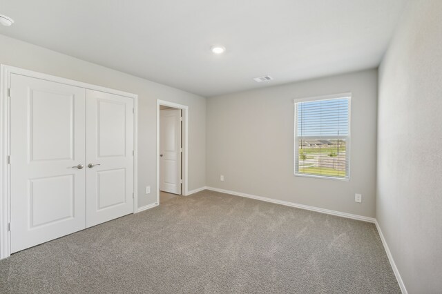 unfurnished bedroom with a closet and light colored carpet