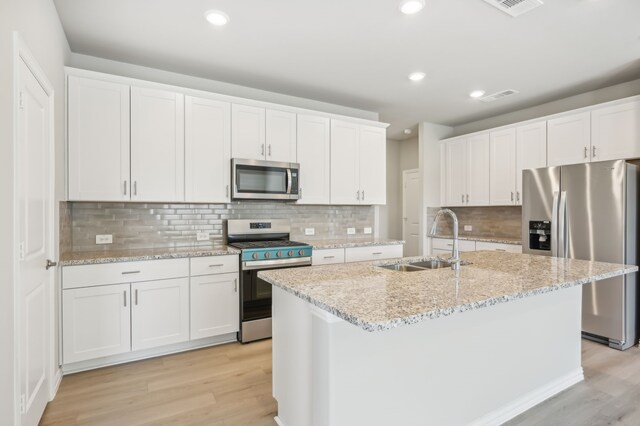 kitchen featuring white cabinetry, sink, light hardwood / wood-style floors, a center island with sink, and appliances with stainless steel finishes