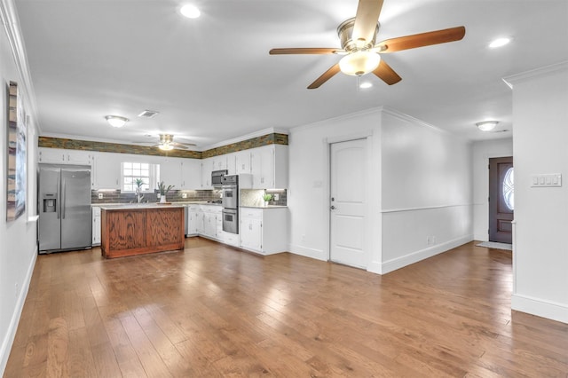 kitchen with white cabinetry, a center island, light hardwood / wood-style flooring, appliances with stainless steel finishes, and ornamental molding