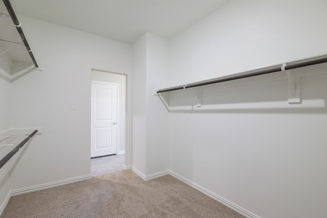 unfurnished bedroom featuring light carpet, ensuite bath, vaulted ceiling, and ceiling fan