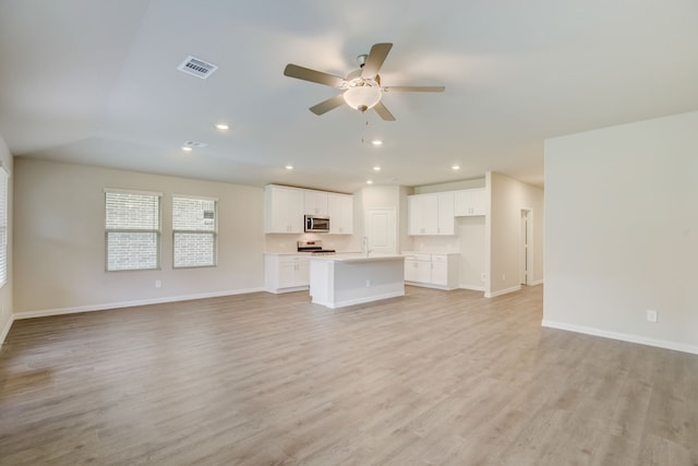 kitchen with white cabinets, an island with sink, and light hardwood / wood-style floors