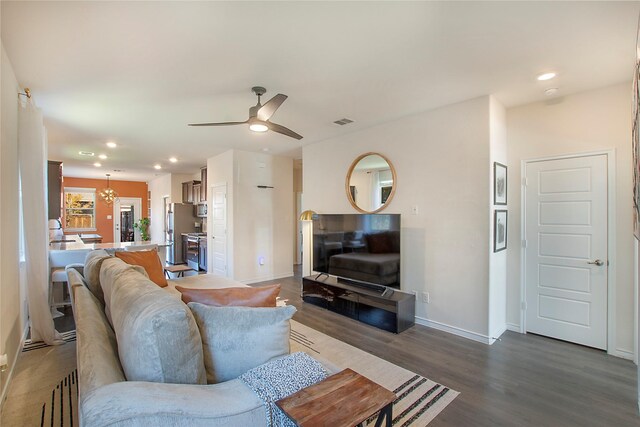 living room with ceiling fan with notable chandelier and hardwood / wood-style flooring