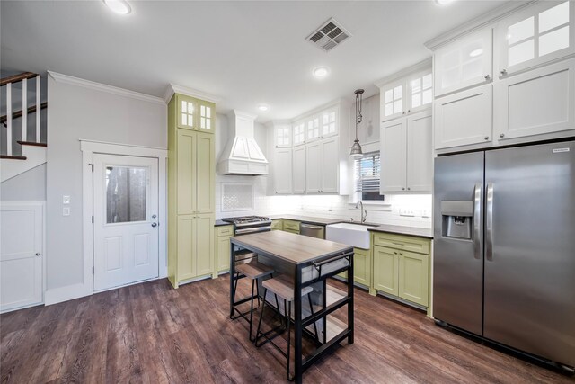 kitchen featuring appliances with stainless steel finishes, dark hardwood / wood-style flooring, ornamental molding, custom exhaust hood, and pendant lighting