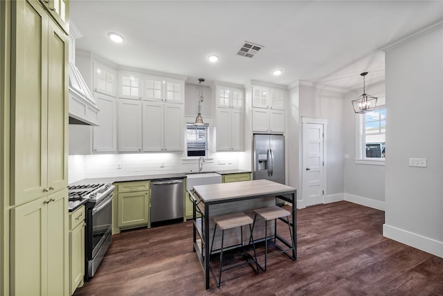 kitchen featuring dark wood-type flooring, white cabinets, green cabinets, hanging light fixtures, and appliances with stainless steel finishes