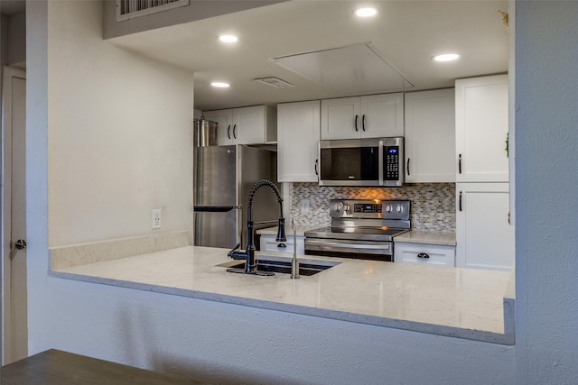 kitchen featuring sink, light stone counters, decorative backsplash, white cabinets, and appliances with stainless steel finishes