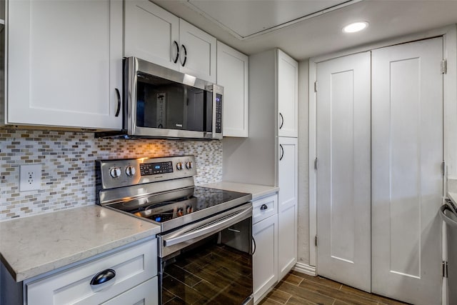 kitchen with light stone countertops, dark hardwood / wood-style flooring, white cabinetry, and stainless steel appliances