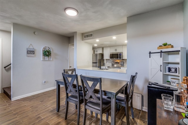 dining room featuring a barn door, sink, and dark wood-type flooring