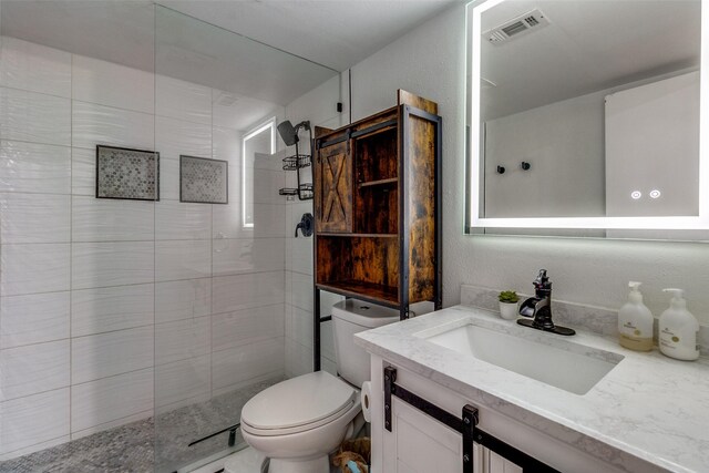 bathroom featuring tiled shower, vanity, and toilet