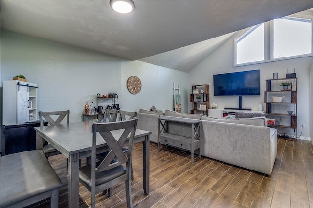 dining room with lofted ceiling, a barn door, and dark wood-type flooring