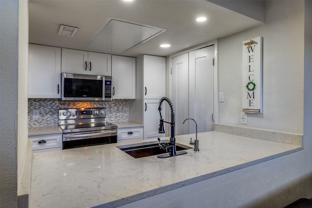 kitchen with white cabinets, sink, light stone countertops, and stainless steel appliances