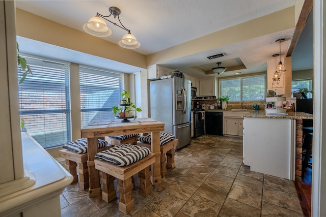 kitchen featuring pendant lighting, white cabinetry, sink, black dishwasher, and stainless steel fridge with ice dispenser