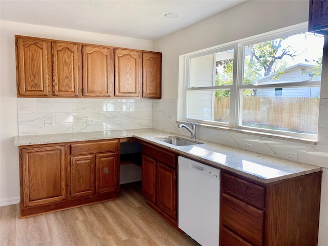 kitchen with white dishwasher, light stone countertops, sink, and backsplash